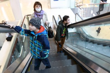 Anne ve oğulları alışveriş merkezinde yürüyen merdivende.