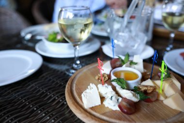 Restoranda ahşap tabakta çeşitli peynir parçaları.