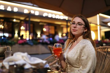 Geceleri kafede aperol sprey kokteyli içen kadın portresi