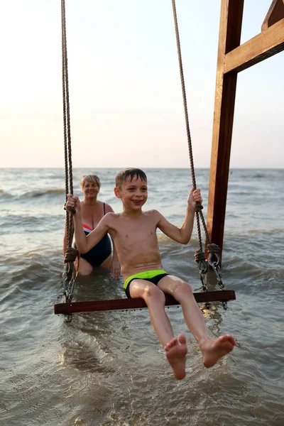 Frau Rockt Glücklichen Jungen Auf Schaukel Asowschen Meer Bei Sonnenuntergang — Stockfoto