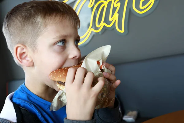 Hungry child biting burger in a restaurant