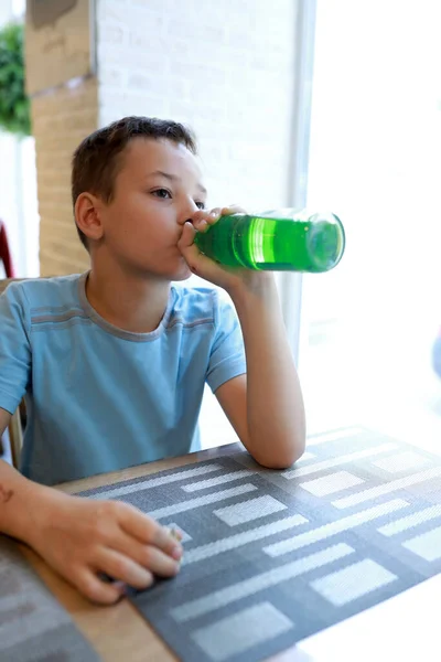 Child drinking lemonade from bottle in restaurant