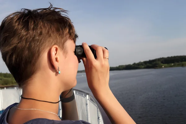 Vrouw die door een verrekijker kijkt — Stockfoto