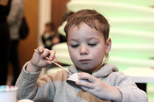 Preschooler paints a cardboard toy — Stock Photo, Image