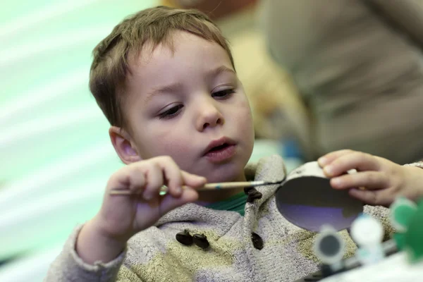 Kid paints a cardboard toy — Stock Photo, Image