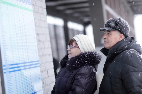 Couple looks at train schedule — Stock Photo, Image