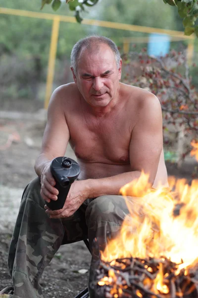 Uomo che ventilava il fuoco al picnic — Foto Stock