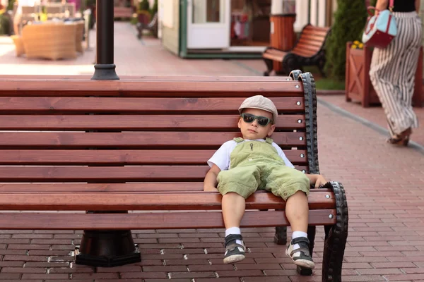 Barnet vilar på en bänk — Stockfoto