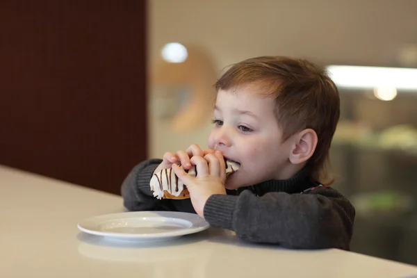 Criança comer eclair — Fotografia de Stock