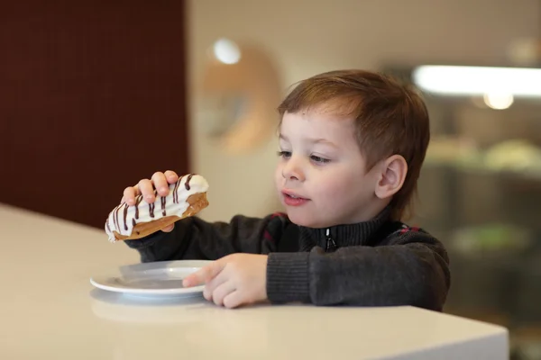 Junge isst Eclair — Stockfoto