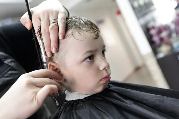 Peluquero cortar el pelo de un chico serio — Foto de Stock
