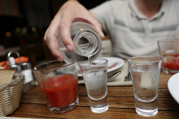Person gießt Wodka aus einer Karaffe — Stockfoto