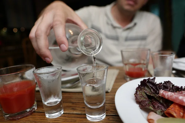 Mann schüttet Wodka aus einer Karaffe — Stockfoto