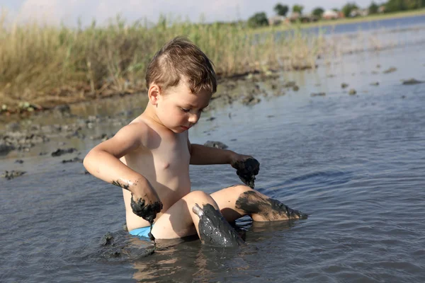 Мальчик сидит в лечебной грязи — стоковое фото