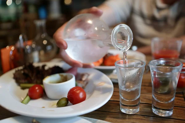 Person pouring vodka from the decanter — Stock Photo, Image