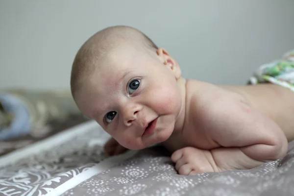 Nadenkend pasgeboren babyjongen op een bed — Stockfoto