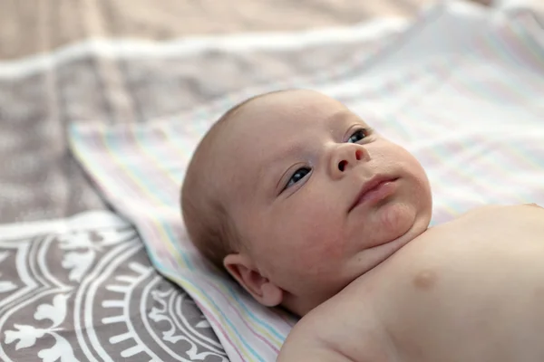 Thinking baby on a bed — Stock Photo, Image