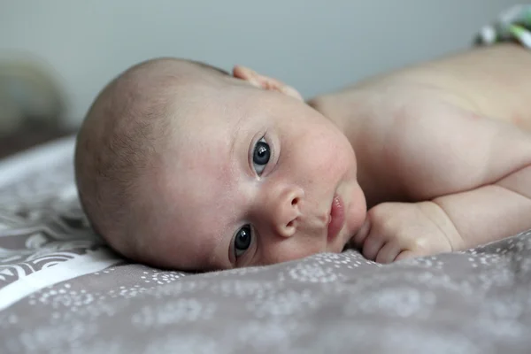 Nadenkend pasgeboren baby op een bed — Stockfoto