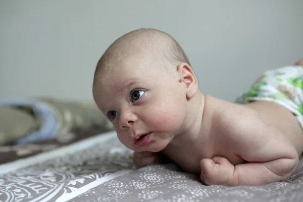 Serious baby on a bed — Stock Photo, Image