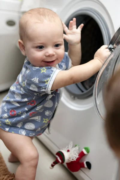 Улыбающийся мальчик со стиральной машиной — стоковое фото