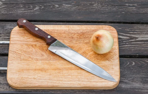 Cuchillo, cebolla y tabla de cortar — Foto de Stock
