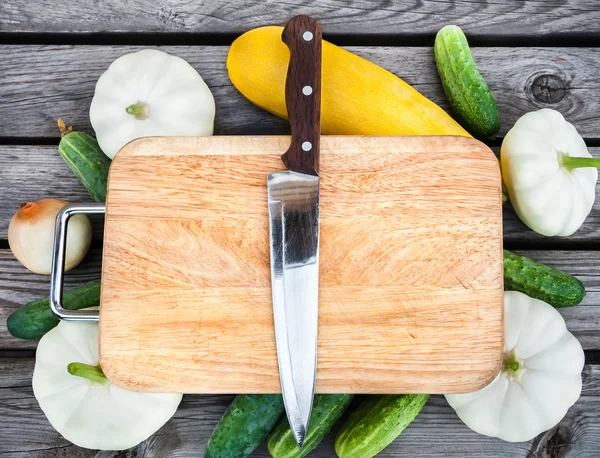 Skärbräda, kniv, färska grönsaker på träbord. Top vie — Stockfoto