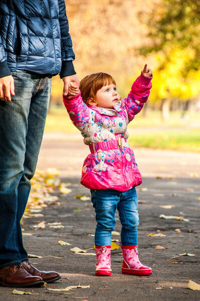 Little girl walks with my dad, pointing to something in the park