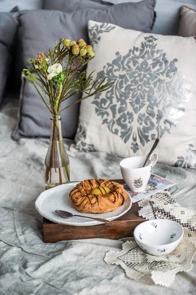 Cup of coffee, bun and flowers — Stock Photo, Image