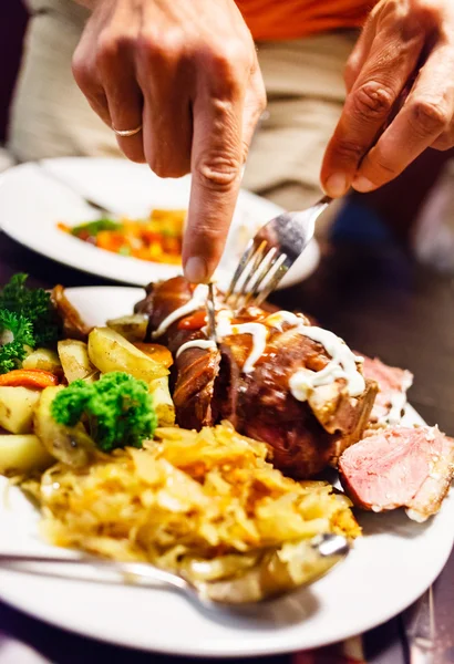 man eating knuckle of pork