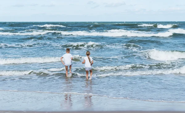 Αγόρι και κορίτσι με τα κύματα της θάλασσας — Φωτογραφία Αρχείου