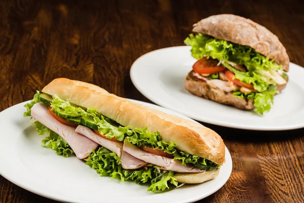 Tasty sandwiches on white plates — Stock Photo, Image