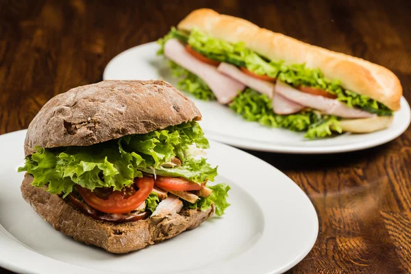 Tasty sandwiches on white plates — Stock Photo, Image