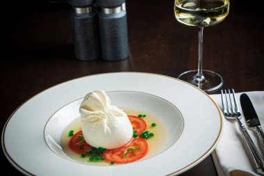 Beyaz tabakta servis edilen İtalyan peynirli burrata.