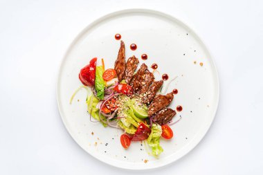 Beyaz tabakta ızgara sebzeli biftek.