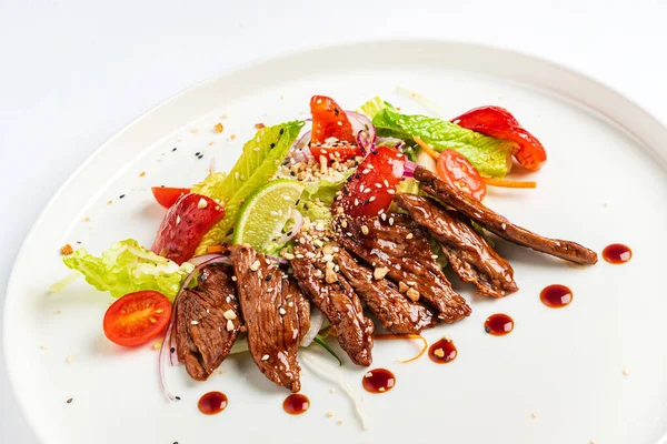 Beyaz tabakta ızgara sebzeli biftek.