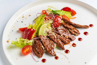 Beyaz tabakta ızgara sebzeli biftek.