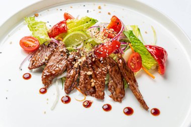 Beyaz tabakta ızgara sebzeli biftek.