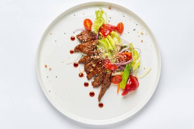 Beyaz tabakta ızgara sebzeli biftek.