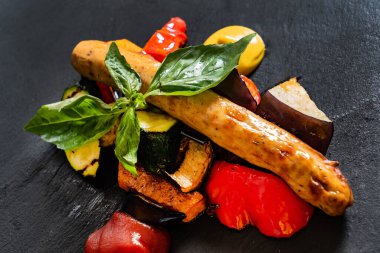 Siyah arka planda sebzeli sosis.