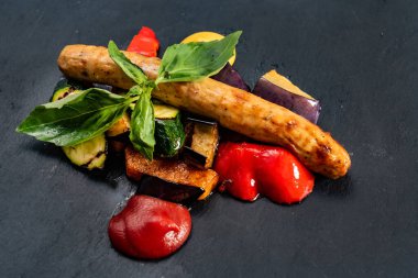 Siyah arka planda sebzeli sosis.