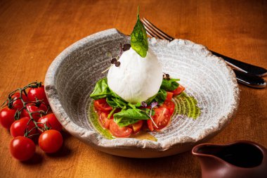 Beyaz tabakta servis edilen domatesli İtalyan peyniri.