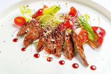 Beyaz tabakta ızgara sebzeli biftek.