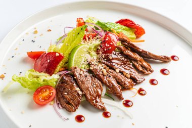 Beyaz tabakta ızgara sebzeli biftek.