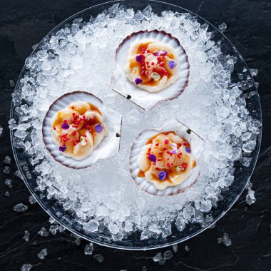 Taş tahtadaki istiridyelerin tazeliği. Tazelik için istiridye kabuğu açtım. İki yarı açık kabuklu limon ve limonlu siyah taş zemin.