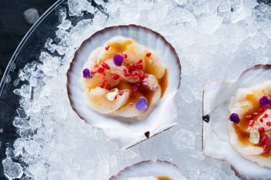 Taş tahtadaki istiridyelerin tazeliği. Tazelik için istiridye kabuğu açtım. İki yarı açık kabuklu limon ve limonlu siyah taş zemin.