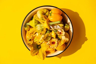 Sarı sebzeler ve çiçekler kasede.