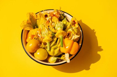 Sarı sebzeler ve çiçekler kasede.