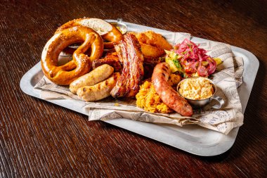 Oktoberfest bira menüsü geleneksel köy usulü, dana kraker, ahşap masa üzerinde beyaz tabakta hardallı sosis..