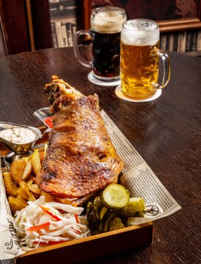 Geleneksel gurme Alman atıştırmalığı kızarmış patates, kızarmış sebzeli ızgara domuz kaburgası, ızgara panelinde bıçak ve bira..