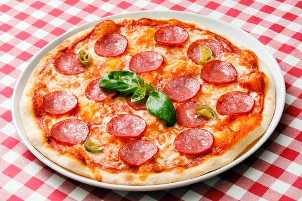 Tasty pizza on checkered tablecloth — Stock Photo, Image